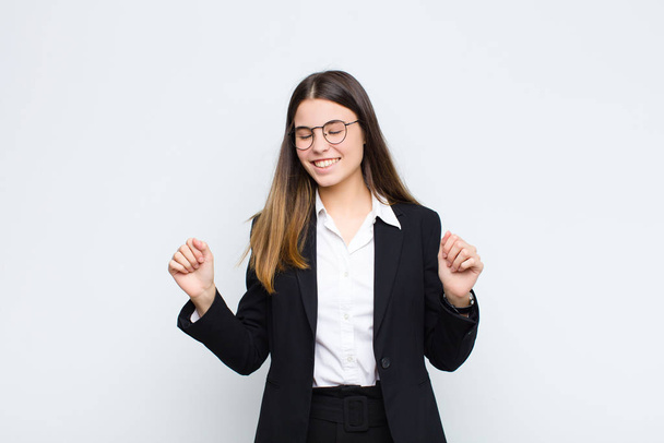 young businesswoman looking extremely happy and surprised, celebrating success, shouting and jumping against white wall - Φωτογραφία, εικόνα