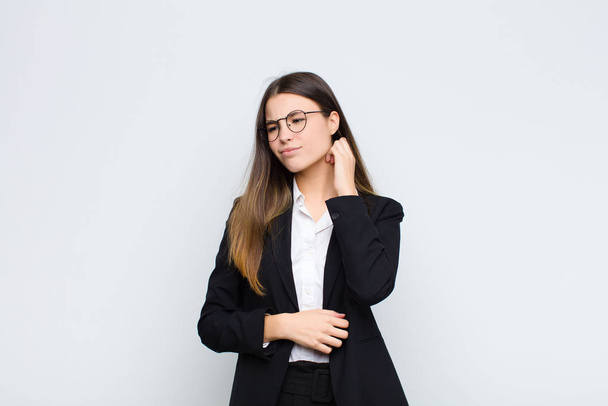 young businesswoman feeling stressed, frustrated and tired, rubbing painful neck, with a worried, troubled look against white wall - Zdjęcie, obraz