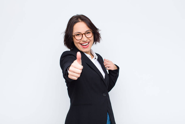 young businesswoman feeling proud, carefree, confident and happy, smiling positively with thumbs up against white wall - Photo, Image