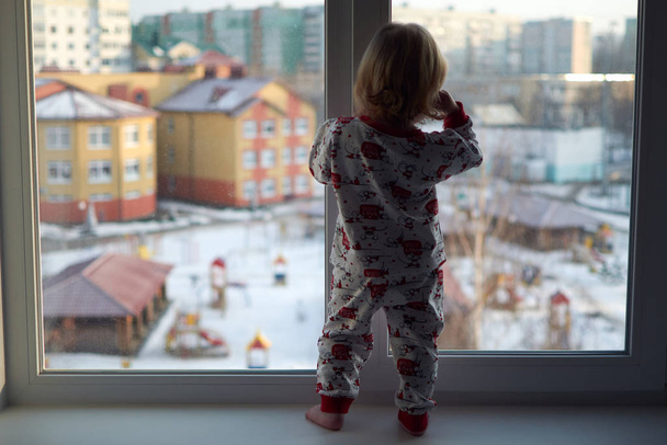 A little girl standing in front of a window - Фото, изображение