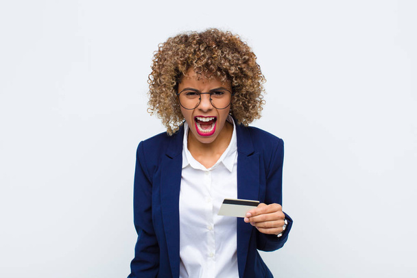 young african american woman shouting aggressively, looking very angry, frustrated, outraged or annoyed, screaming no with a credit card - Foto, immagini