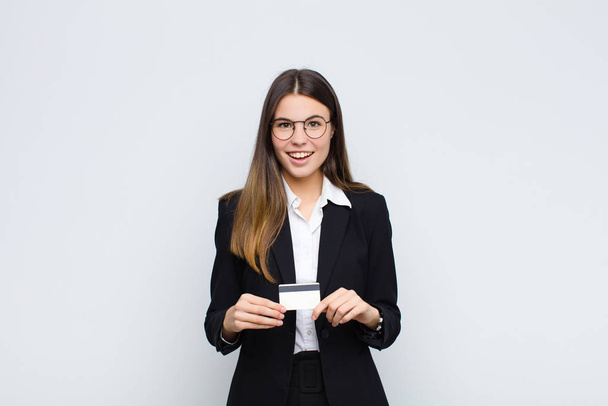young pretty woman looking happy and pleasantly surprised, excited with a fascinated and shocked expression with a credit card - Фото, зображення
