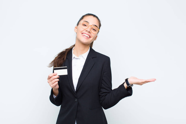 young businesswoman smiling cheerfully, feeling happy and showing a concept in copy space with palm of hand with banknotes with bills - Foto, imagen