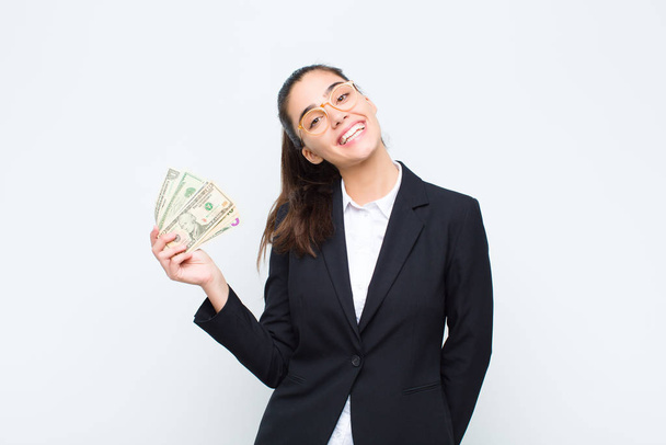 young businesswoman looking happy and pleasantly surprised, excited with a fascinated and shocked expression with banknotes with bills - Photo, image