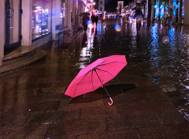秋のタリン旧市街の夜の通りのカフェ街の光ピンクの傘雨季の通りの夜の光都市の人々の天気風景、ヨーロッパの休日への旅行をぼやけている  - 写真・画像