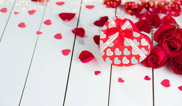 Szív alakú ajándék doboz és vörös rózsa fehér fa asztalon - Fotó, kép