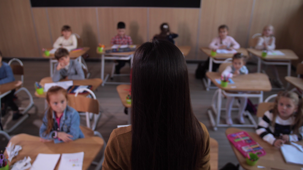 Professor em pé na frente dos alunos em sala de aula
 - Filmagem, Vídeo