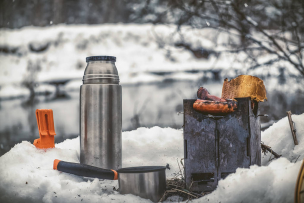 Piknik kalastusmatkalla, lumen peittämällä talvijoella
. - Valokuva, kuva