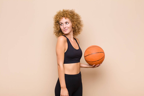 young afro woman smiling gleefully, feeling happy, satisfied and relaxed, with crossed arms and looking to the side sport concept - Photo, Image