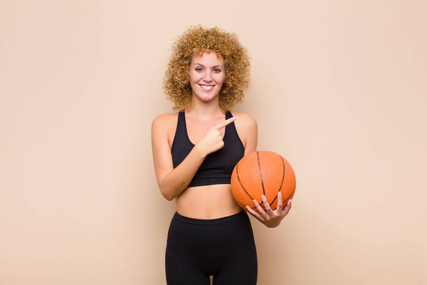 young afro woman smiling happily and pointing to side and upwards with both hands showing object in copy space sport concept - Фото, изображение