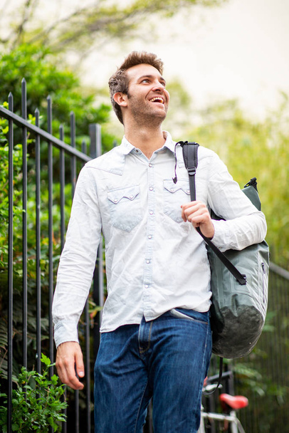 Ritratto di uomo felice che cammina con borsa all'esterno
 - Foto, immagini