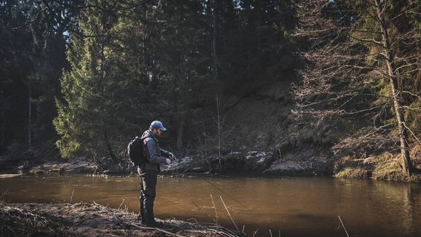 森の川のほとりの漁師たち - 写真・画像