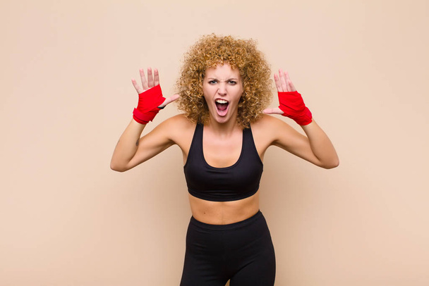 young afro woman screaming in panic or anger, shocked, terrified or furious, with hands next to head sport concept - 写真・画像