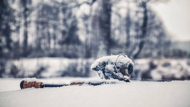 Spinning and reel lie on the snow. - Foto, afbeelding