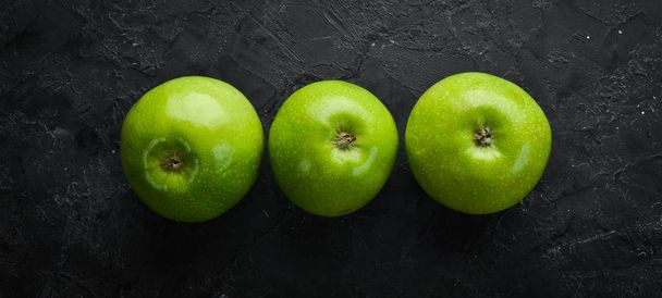 Three fresh green apples on a black stone background. Vegetables. Top view. Free space for your text. - Foto, Imagem