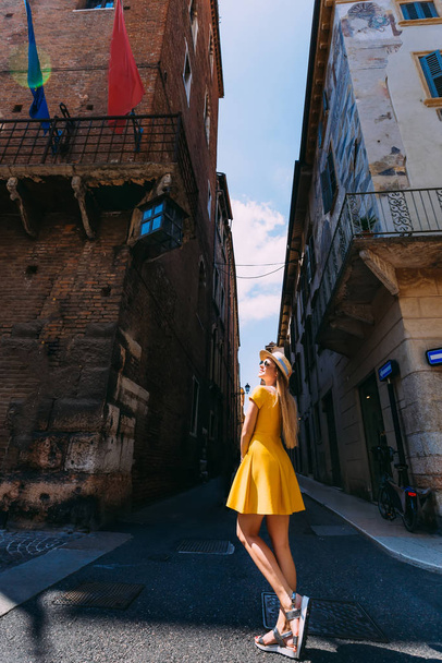 Το κορίτσι με το κίτρινο φόρεμα ποζάρει στους δρόμους της πόλης. Η - Φωτογραφία, εικόνα