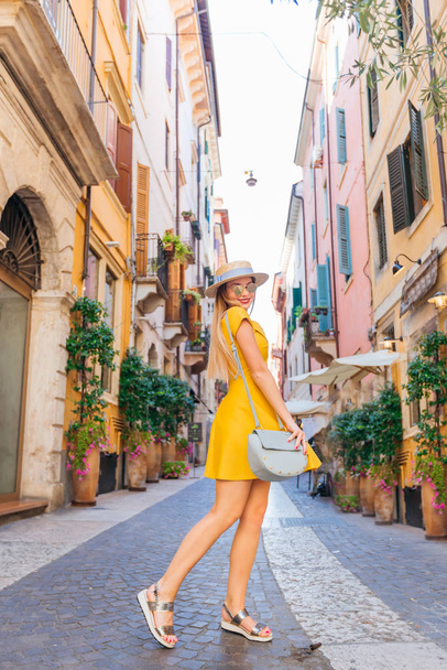 Дівчина в жовтій сукні позує на вулиці міста
 - Фото, зображення
