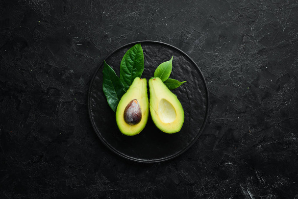 Fresh avocado on black stone background. Citrus fruits. Top view. Free space for your text. - Фото, изображение