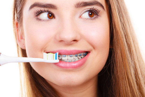 Woman brushing teeth with braces using brush - Photo, image