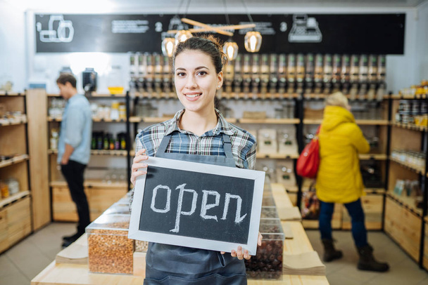 Vrouwelijke ondernemer in bezit Open sign in bakkerij - Foto, afbeelding
