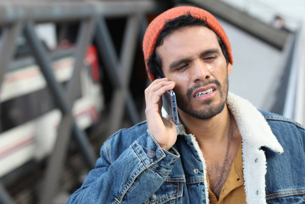 Nuori mies saa huonoja uutisia puhumisen aikana puhelin
  - Valokuva, kuva