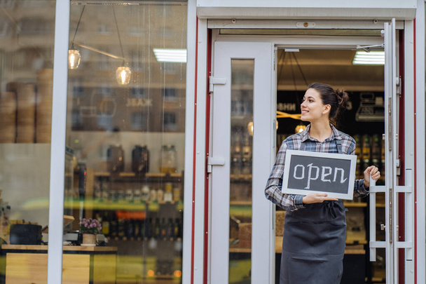 Krásná asijské žena obchod majitel s stojící ve dveřích její kavárny při pohledu na kameru a smiling.Portrét dívky servírka na sobě zástěru a stojí před - Fotografie, Obrázek