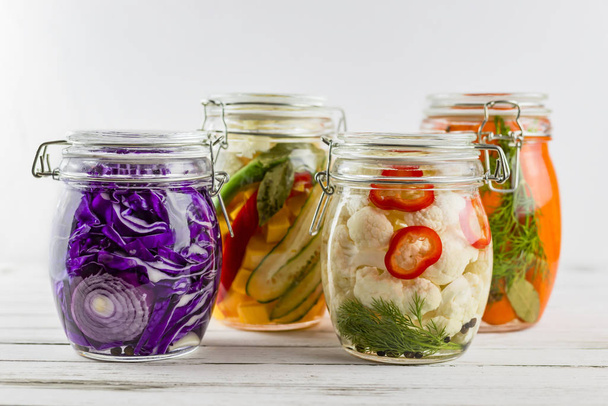 glass jars of fermented red cabbage, cauliflower, carrots, vegetables on a light background. fermentation is a source of probiotic. - Photo, Image