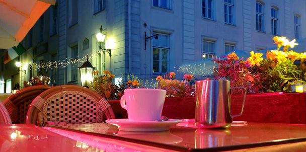  uliczna kawiarnia w nocy filiżanka kawy na stole w ulicznej kawiarni Tallinn stare miasto zamazane panoramiczne tło wakacje podróż do Europy Estonia  - Zdjęcie, obraz