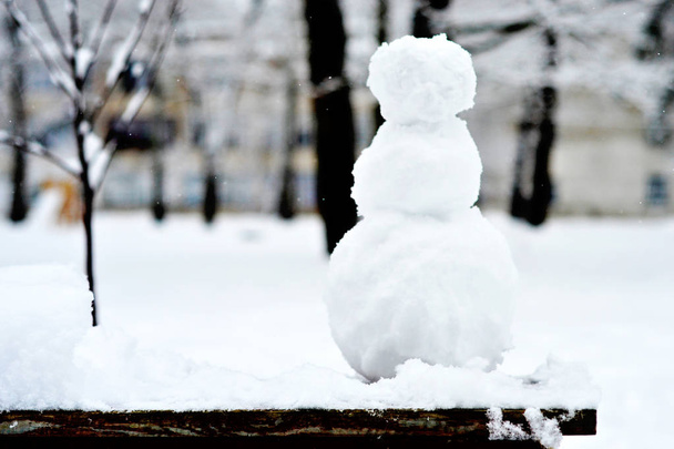 Pequeno boneco de neve ficando no banco
. - Foto, Imagem