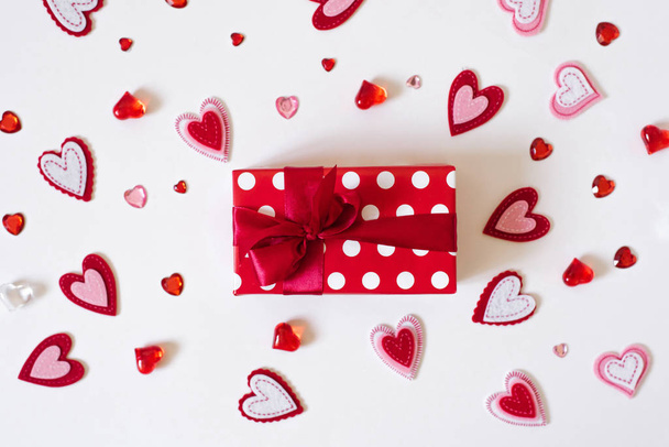 Kırmızı saten kurdeleli bir hediye ve beyaz arka planda bir kalp..  - Fotoğraf, Görsel