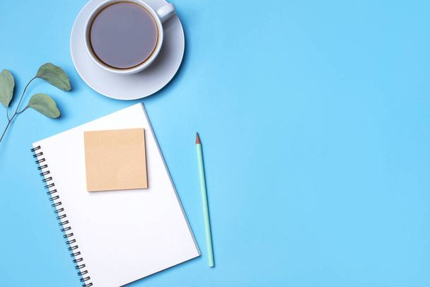 Blue background with notepad, pencil and cup of coffee. - Photo, image