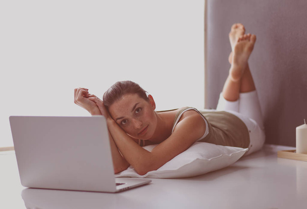 A young woman lying on the floor with a laptop - Foto, Imagen