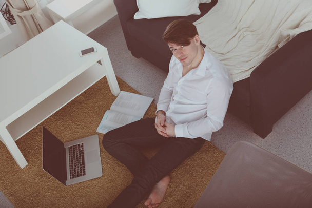 Hombre casual usando ordenador portátil en casa sentado en el suelo en la sala de estar
 - Foto, Imagen