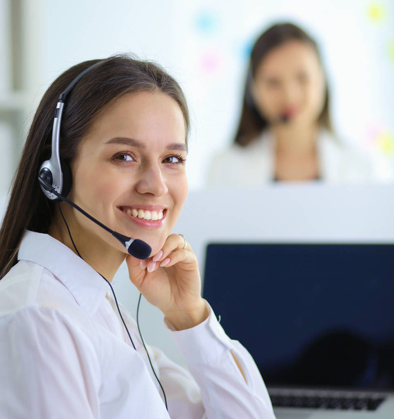 Smiling businesswoman or helpline operator with headset and computer at office - Photo, image