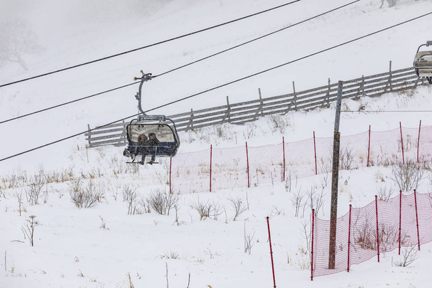 Menschen, die bei Schneefall eine Seilbahn hinunter klettern - Foto, Bild