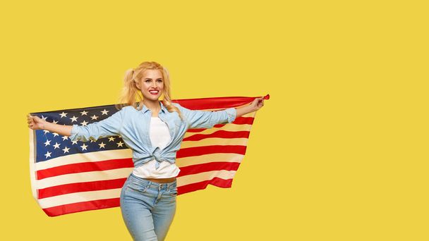 American girl. Happy young woman in denim clothes holding USA flag on yellow background. Banner. Copy space for text. football fan - Foto, Imagen