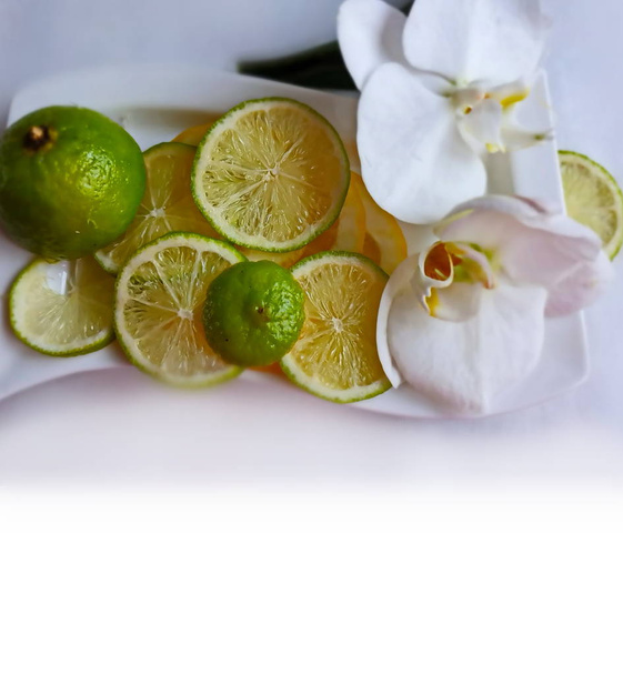 Limon dilimleri turunçgiller ve limon turunçgilleri mavi tabakta sulu meyveler natürmort hayat, orkide çiçekli sağlıklı yiyecekler yeşil ve sarı gıda dekorasyonu tropikal  - Fotoğraf, Görsel