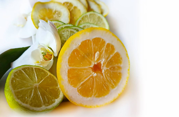 Lemon Plastry owoców cytrusowych i cytryny soczyste plasterki owoców na niebieskiej płycie tła martwa natura, zdrowe jedzenie i vitamiin z kwiatami storczyków, zielony i żółty dekoracji żywności projekt  - Zdjęcie, obraz