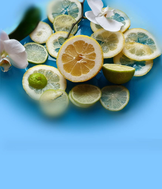 Limón Rebanadas cítricos y cítricos de lima jugosa rebanada de fruta en el fondo del plato azul bodegón, alimentos saludables y vitamiina con flores de orquídeas, diseño de decoración de alimentos verdes y amarillos
  - Foto, imagen