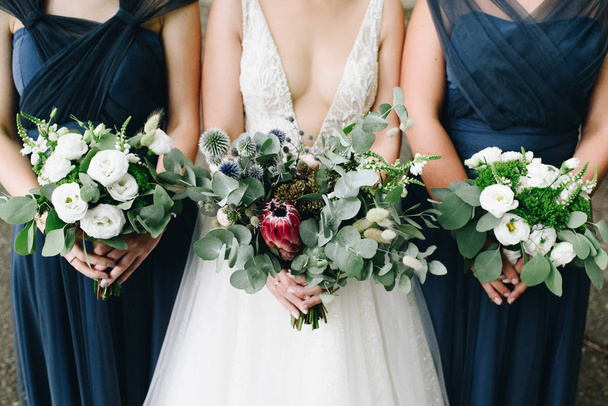 Noiva e suas damas de honra segurando seus buquês de flores na frente deles
 - Foto, Imagem
