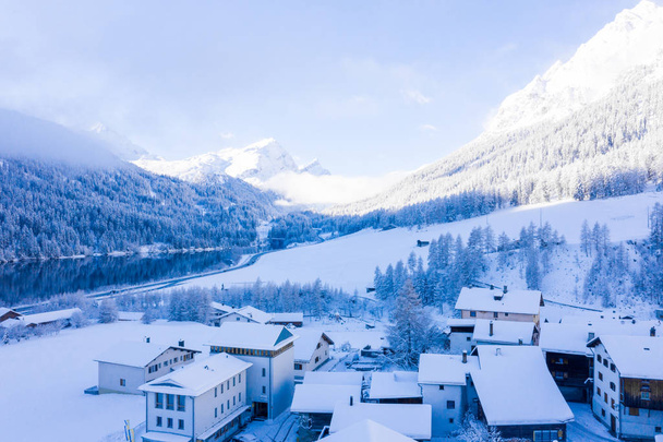 Panoramic view of scenic winter landscape in Swiss Alps with famous Church in the center of the village. Mighty Alpine mountains around the village. Real winter. - Φωτογραφία, εικόνα