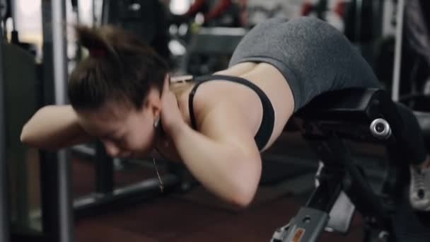 Young woman making hyperextension exercise at the gym - Filmati, video