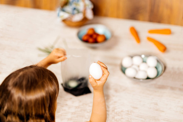 Молодая девушка готовит пасхальные яйца для смерти с пищевым красителем. Выборочный фокус. Пасхальный праздник
 - Фото, изображение