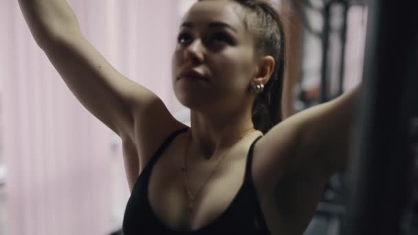 Young woman at the gym making pull-ups on the horizontal bar - Metraje, vídeo