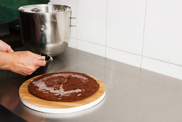 The process of making the chocolate cake, from begin to the end. Made by womans hands for confectionery. Chocolate cakes on a wooden board. - Foto, Bild