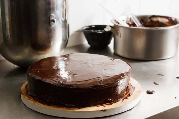 Prepared chocolate cake with glaze icing, final stage of cooking. The process of making the chocolate cake, from begin to the end. Made by hands for confectionery. - Foto, Imagem