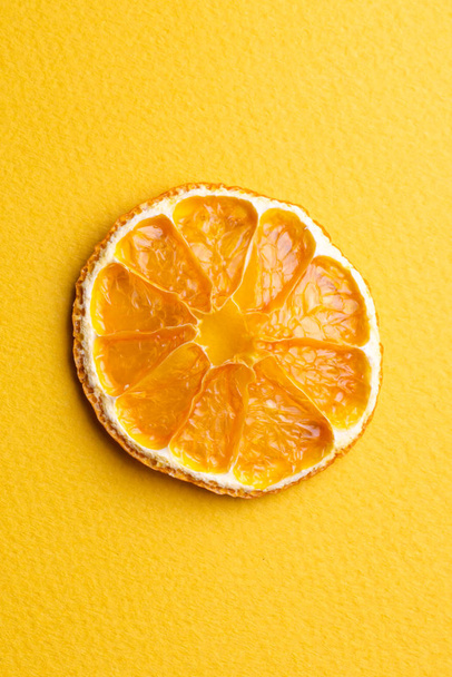 Gedroogde schijfje sinaasappel op een gele achtergrond en plaats voor een in - Foto, afbeelding