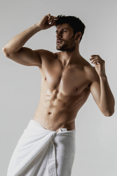 Sexy sport muscle strongface guy with white towel on grey isolated  font background - Foto, imagen