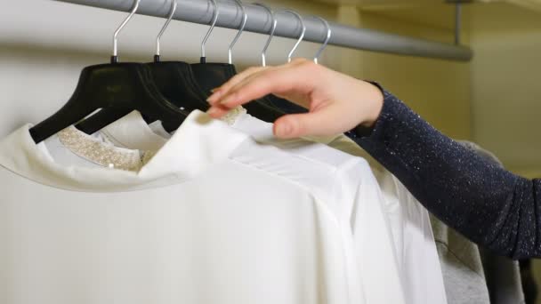 Close-up shot of Female Hand Running on Clothing Hangers Rail Rack and Looking for odzież w sklepie odzieżowym. Koncepcja zakupów. Materiał 4k - Materiał filmowy, wideo
