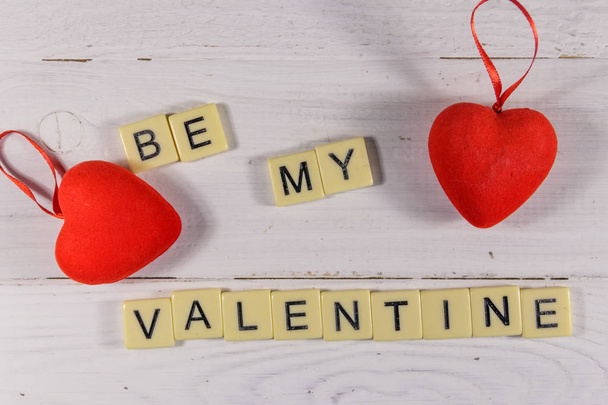 Punaiset sydämet ja "Be my Valentine" teksti valkoisella puupohjalla
 - Valokuva, kuva